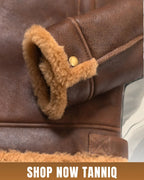 Brown bomber shearling leather jacket with real wool lining and button, featuring 'Shop Now Tanniq' text.