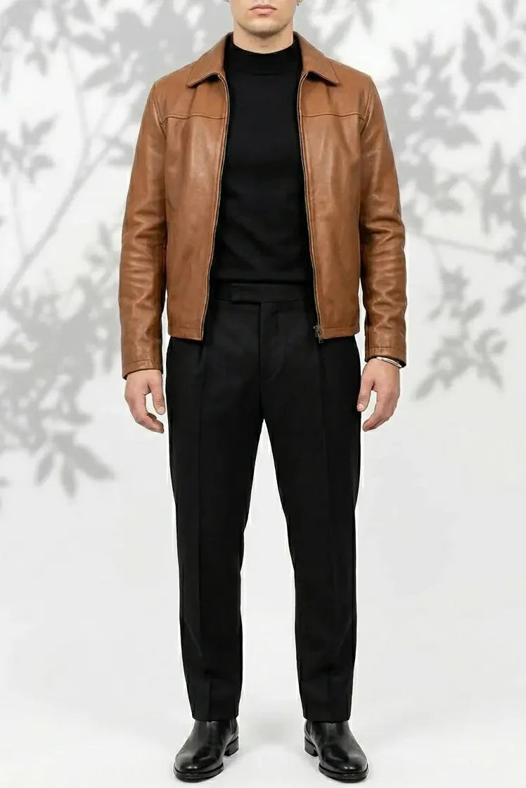 Man wearing a brown leather jacket over a black shirt and pants on a white background