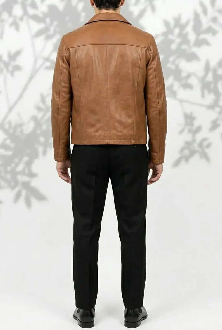 Person wearing a brown leather jacket and black pants against a white background
