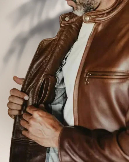 Close-up of a person wearing a brown leather jacket with a white shirt underneath.